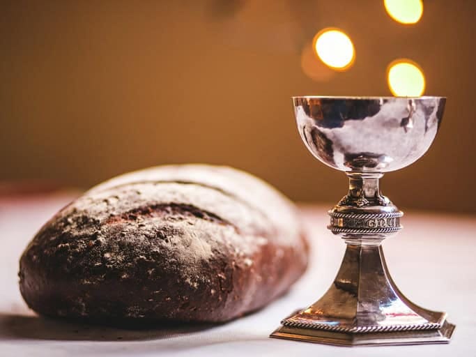 Kelch und Brot als Symbol der Kommunion auf einem Tisch