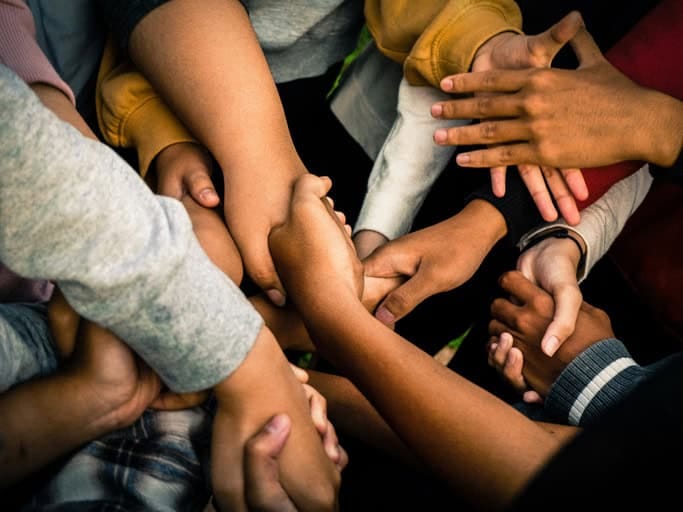 Mehrere Hände liegen übereinander als Symbol für Gemeinschaft und Zusammenhalt