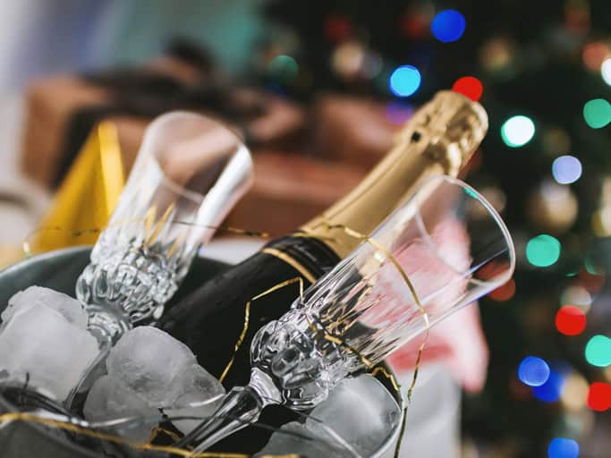 Sektflasche mit zwei Gläsern auf Eis als Symbol für eine Silvesterfeier
